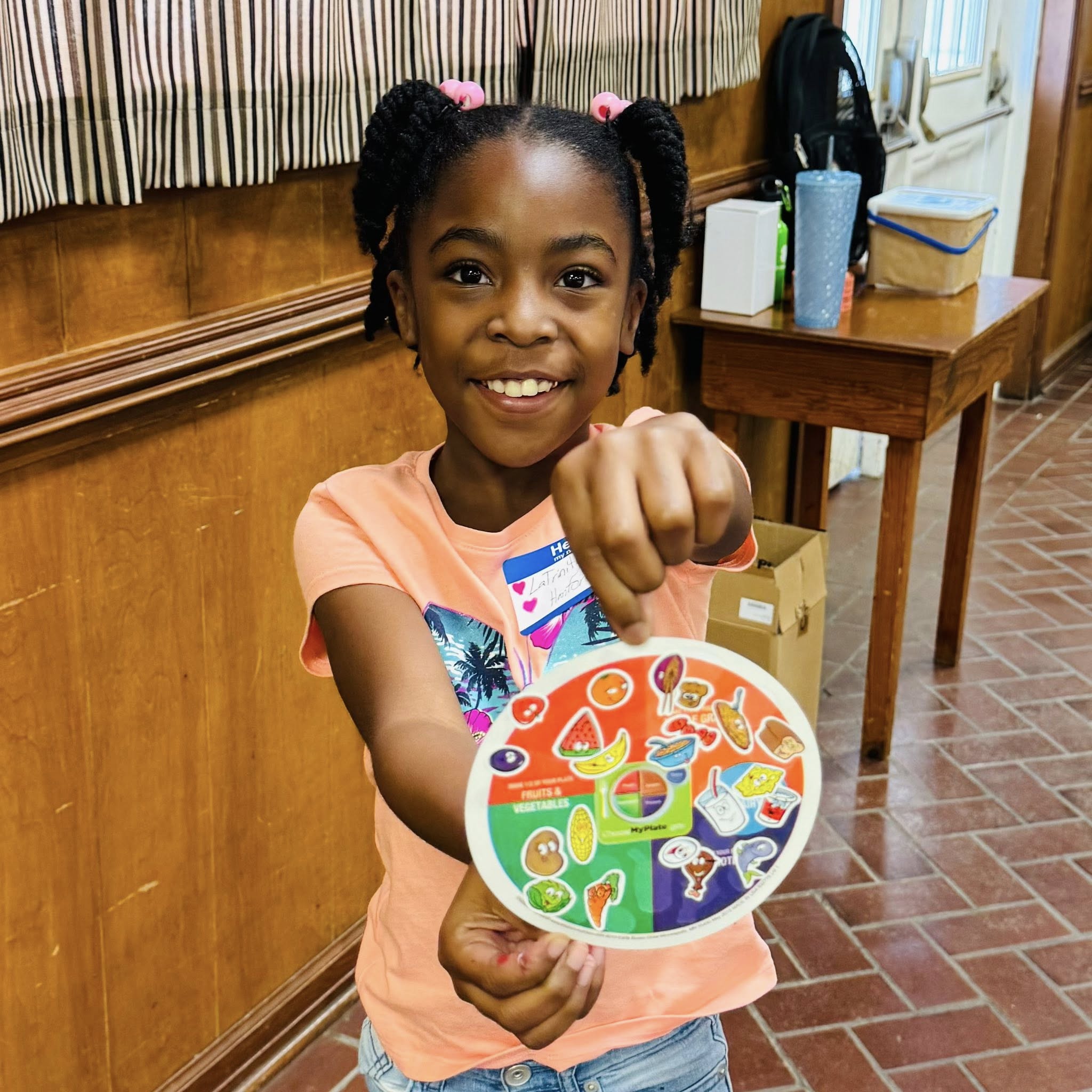 A girl holding a colored paper circle with stickers on it.